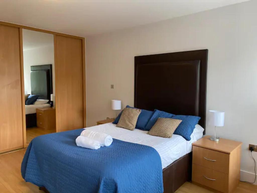 um quarto com uma cama grande com lençóis e almofadas azuis em 2 bed 2 baths in a central location ☆☆☆☆☆ em Basingstoke