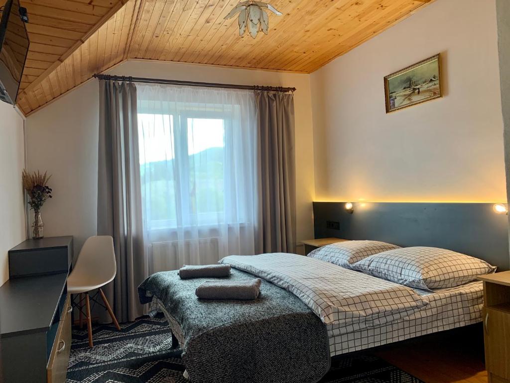 Schlafzimmer mit einem Bett, einem Fenster und einem Schreibtisch in der Unterkunft Ніч над Карпатами in Slawske