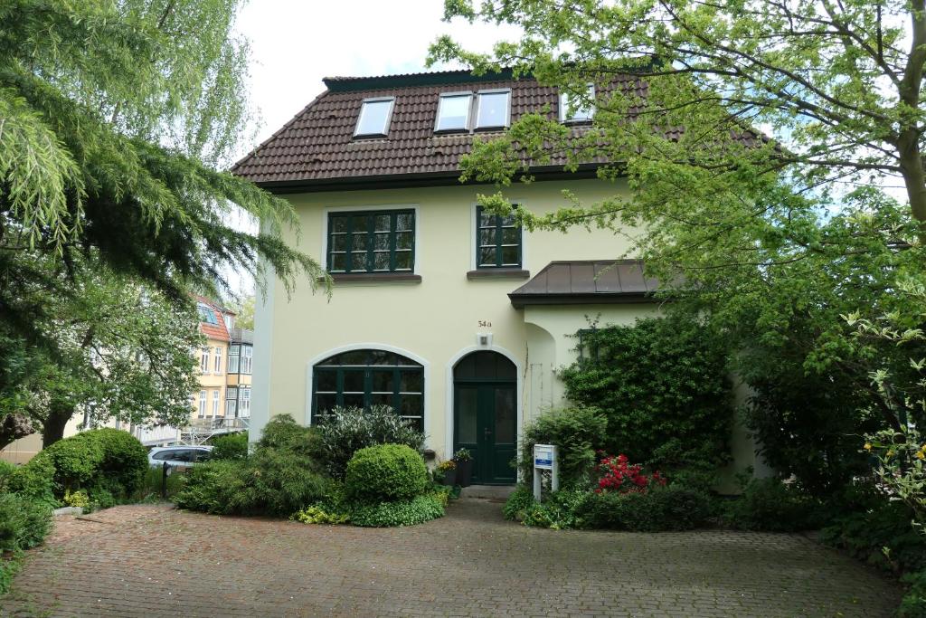 a white house with a black door and trees at Villenappartement mit Blick ins Grüne am Rande der wunderschönen Altstadt in Wismar