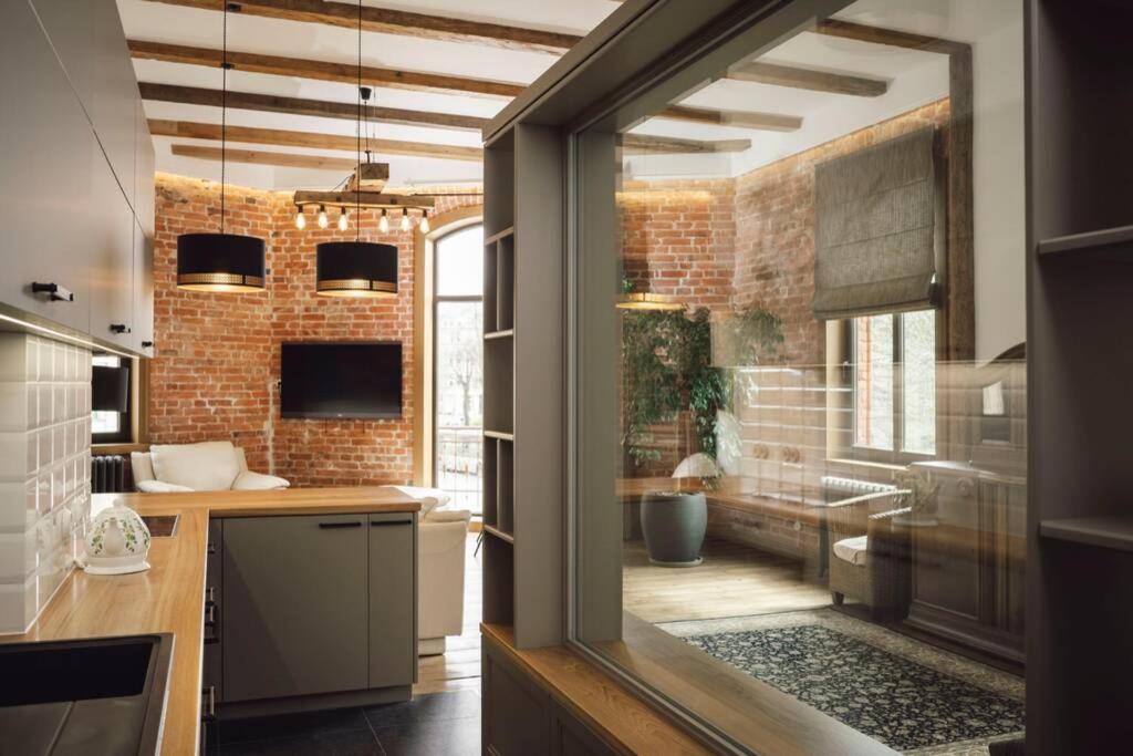 a kitchen with a brick wall and a large window at Berchy Studio Apartment in Liepāja