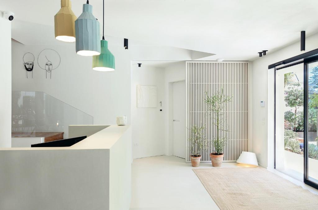 a white kitchen with potted plants and pendant lights at Domìa Boutique Hotel e Cucina in Mondello