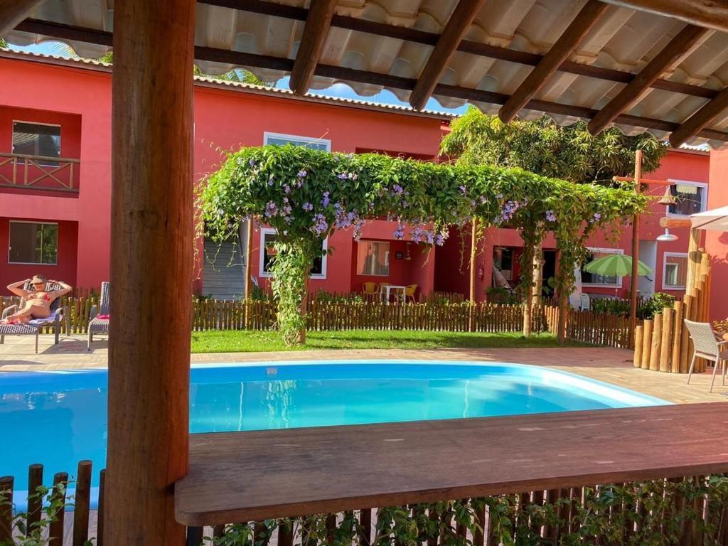 a swimming pool in front of a red house at Ecoville das Mangueiras - Condomínio em Monte Gordo - Região de Guarajuba in Camacari