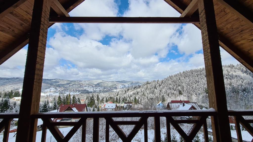 a view of a snowy mountain from a cabin window at Dom na Szewcowej Polanie in Pewel Wielka