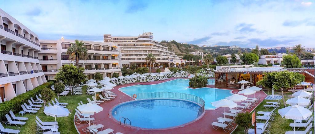 a resort with a large swimming pool and lounge chairs at Sol Cosmopolitan Rhodes in Ixia