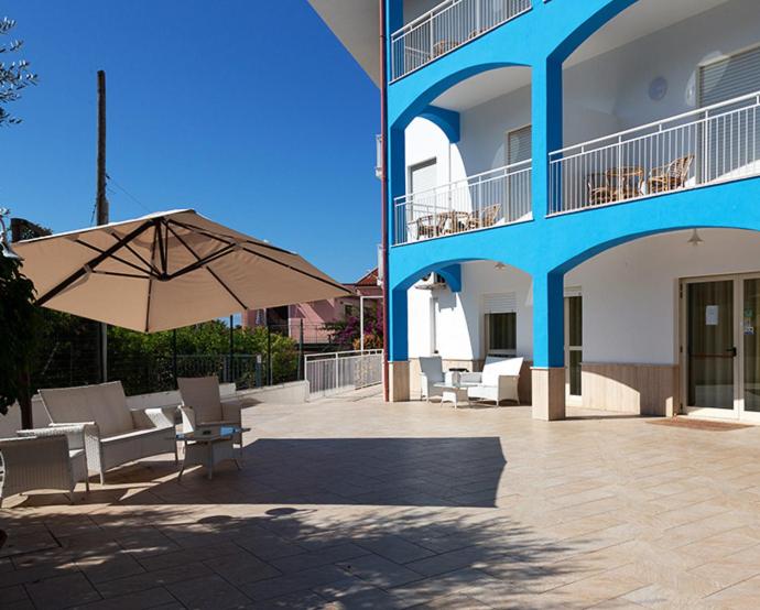 eine Terrasse mit Stühlen und einem Sonnenschirm neben einem Gebäude in der Unterkunft Hotel Parthenius in Cirella