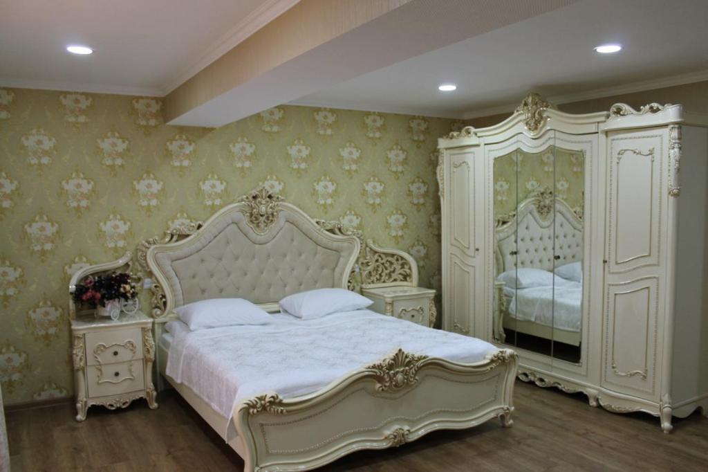 a bedroom with a white bed and two dressers at Hotel Grand Palace in Akhaltsikhe