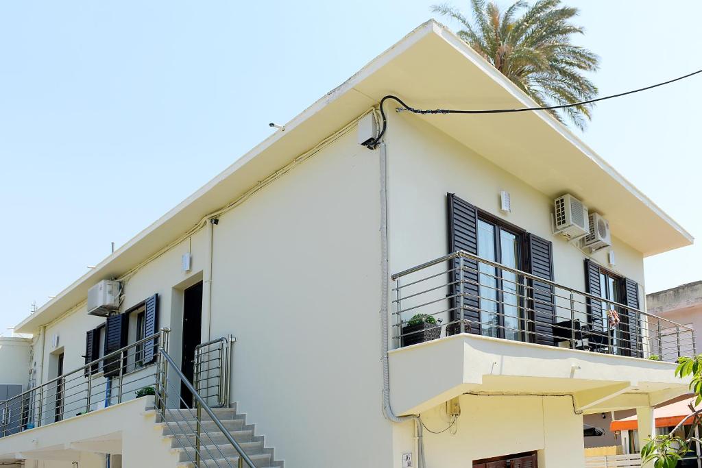 a white building with balconies and a palm tree at Alion House in Rhodes Town