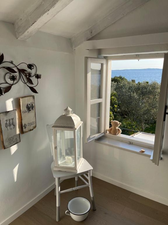 a white room with a window and a table with a lantern at Robinson house Leticia in Cunski