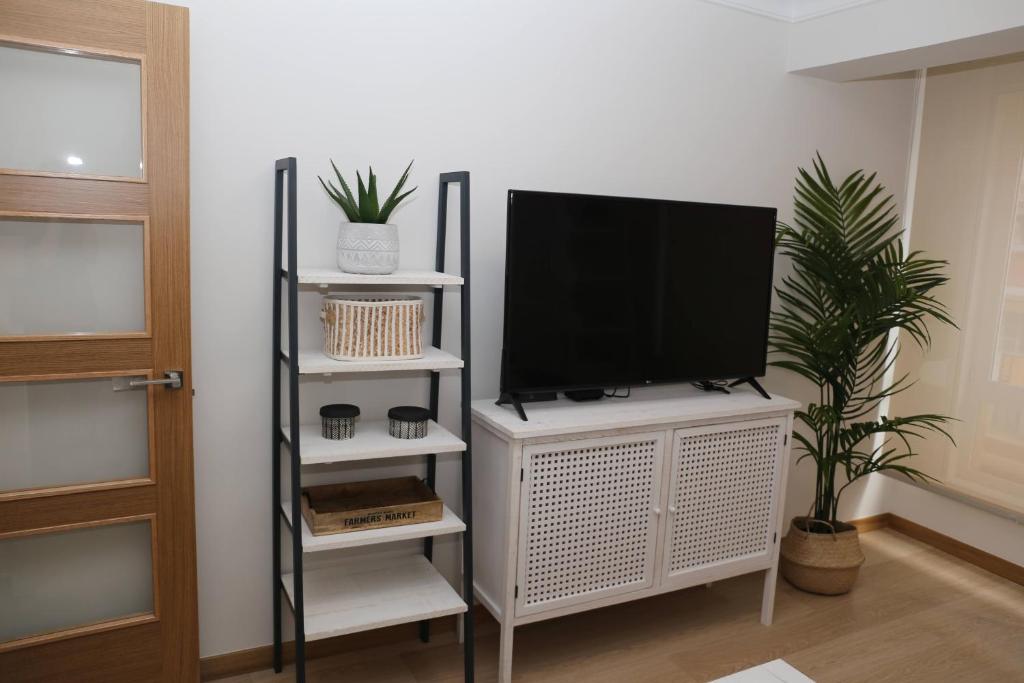 un televisor en un puesto blanco en una habitación en Apartamento Orzán playa, en A Coruña
