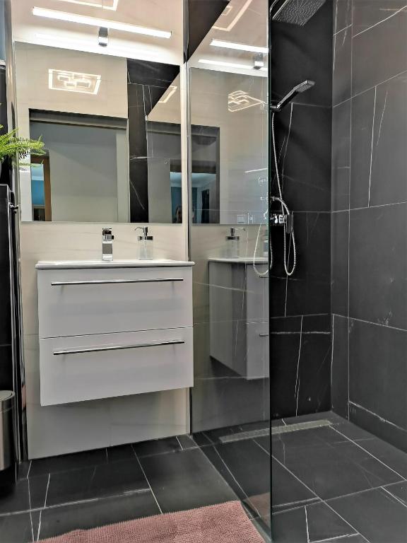 W łazience znajduje się biała umywalka i prysznic. w obiekcie Otium Wellness Apartmanház w mieście Balatonakarattya