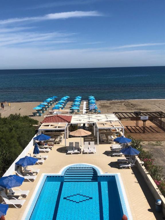 a pool with umbrellas and chairs and the beach at Frank Apartments in Amoudara Herakliou