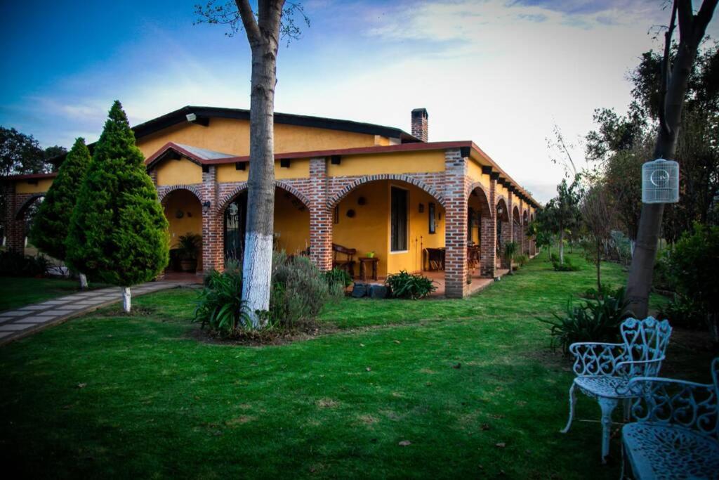 a large brick house with two chairs in a yard at Hacienda Cariño de la Montaña 3000 m2 exclusivos in Tlahuapan