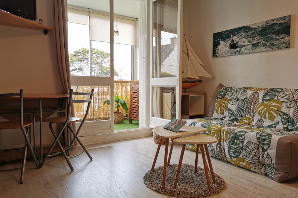 ein Wohnzimmer mit einem Sofa und einem Tisch in der Unterkunft Appartement cosy Roscoff 50 m plage thalasso WIFI PARKING in Roscoff
