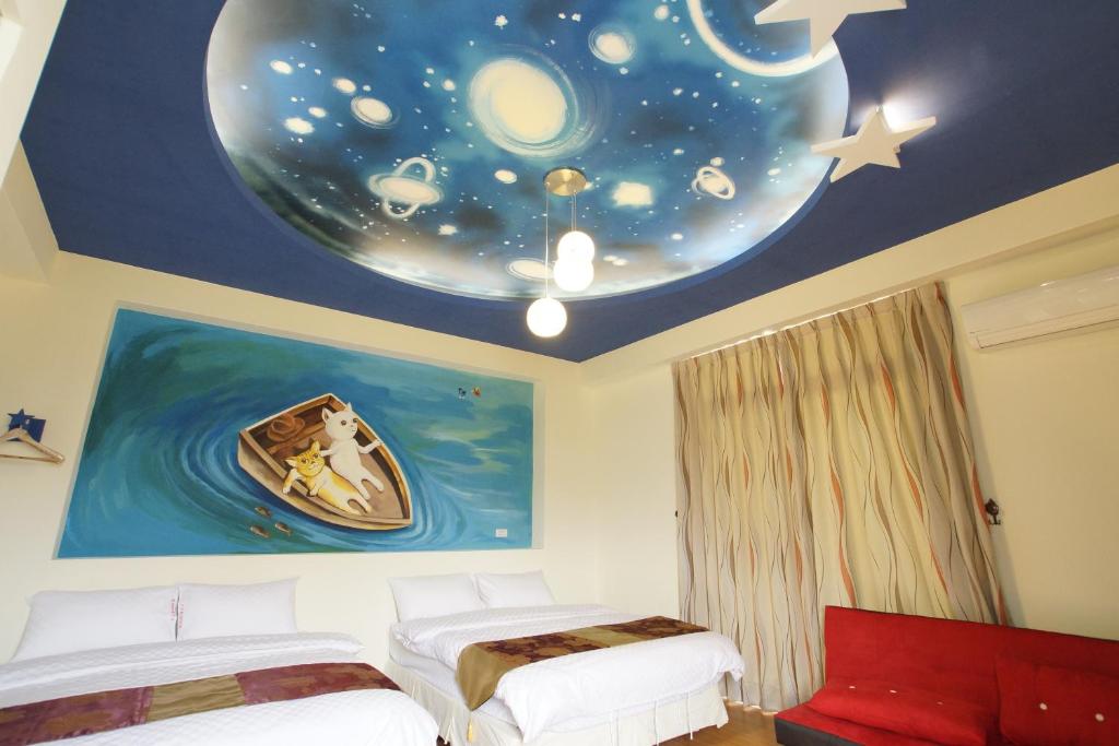 a bedroom with two beds and a moon and stars on the ceiling at 貓咪民宿Mini館-中午即可入房 in Taitung City