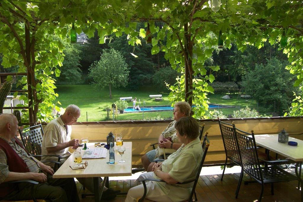 a group of people sitting at tables on a patio at Hotel Dampfmühle in Enkirch