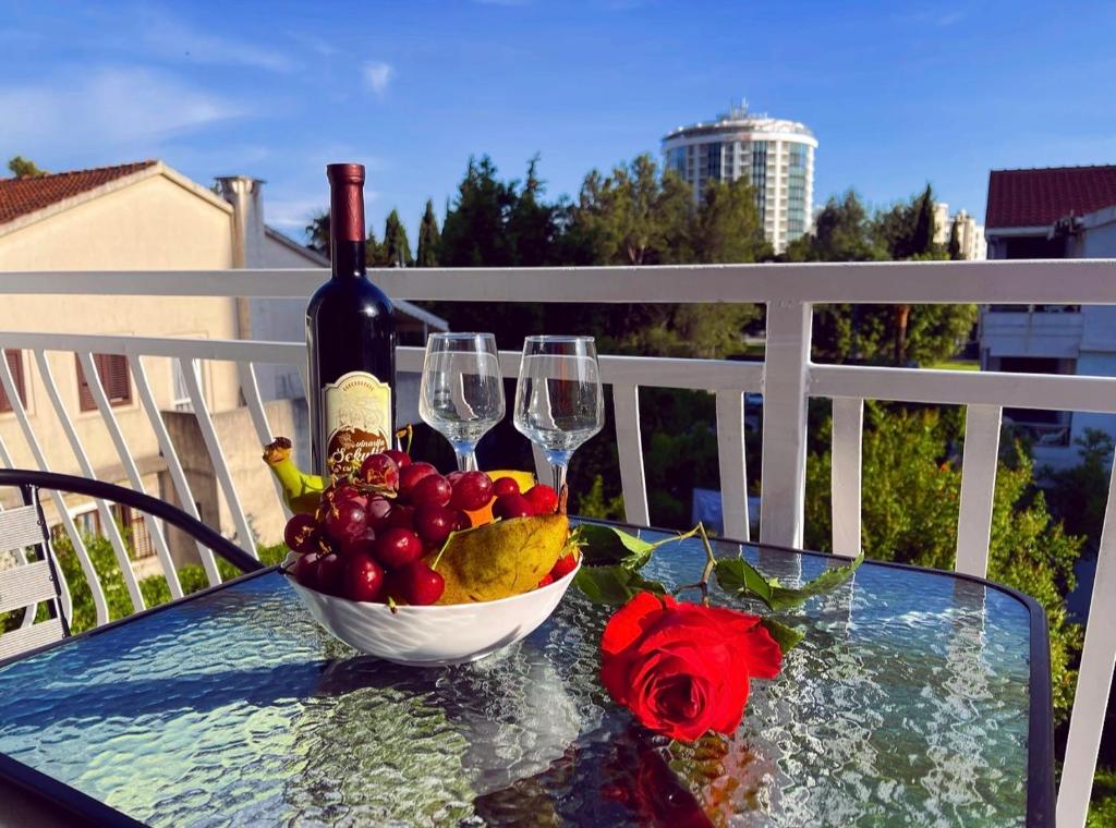 a glass table with a bowl of fruit and wine glasses at Apartmani Agi in Budva