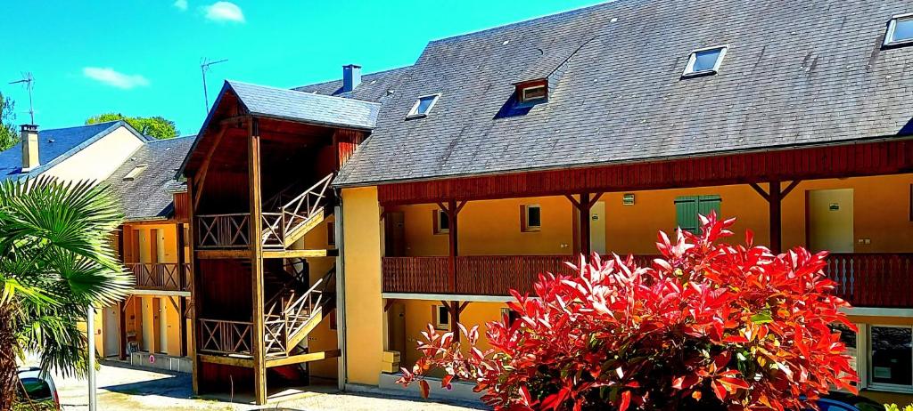 un grand bâtiment jaune avec des fleurs rouges devant lui dans l'établissement Studio très bien situé, belle vue, parking privé, à Bagnères-de-Bigorre