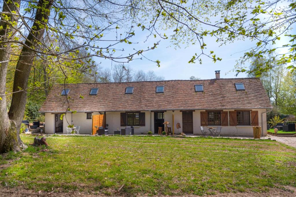 eine Außenansicht eines Hauses mit einem Baum in der Unterkunft GITES du BOIS des PERRUCHES in Saint-Vincent-des-Bois