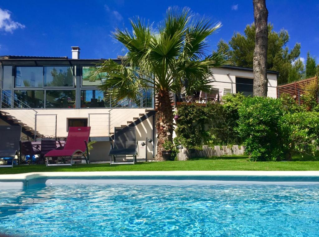 una casa con una palma e una piscina di L'ESCALE COTE BLEUE B&B AND Spa a Sausset-les-Pins