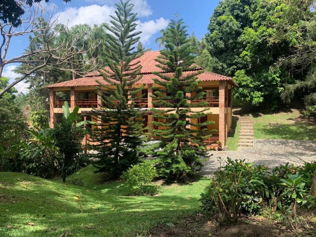 una casa de madera con dos árboles delante de ella en Villa Los Arroyos, en Jarabacoa