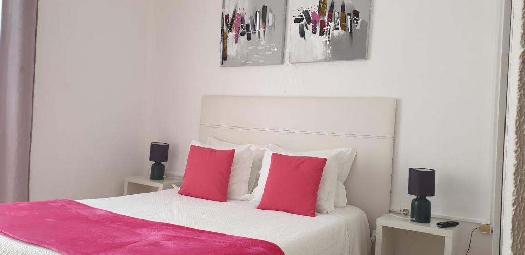 a bedroom with a bed with pink and white pillows at Hotel Palmeira in Aveiro