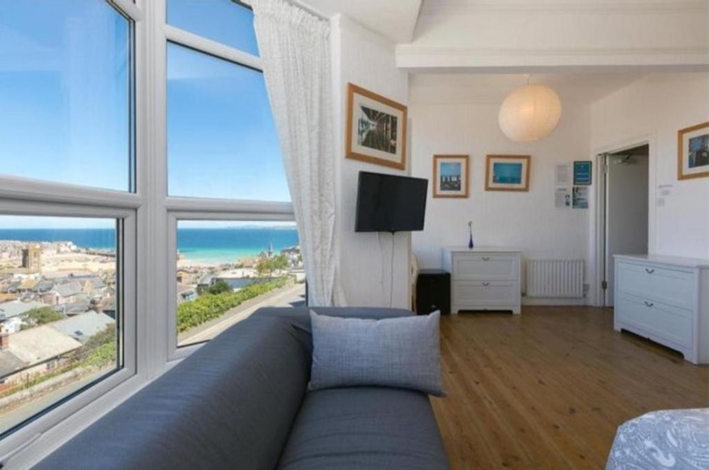 a living room with a blue couch and large windows at Harbour View Guest House in St Ives