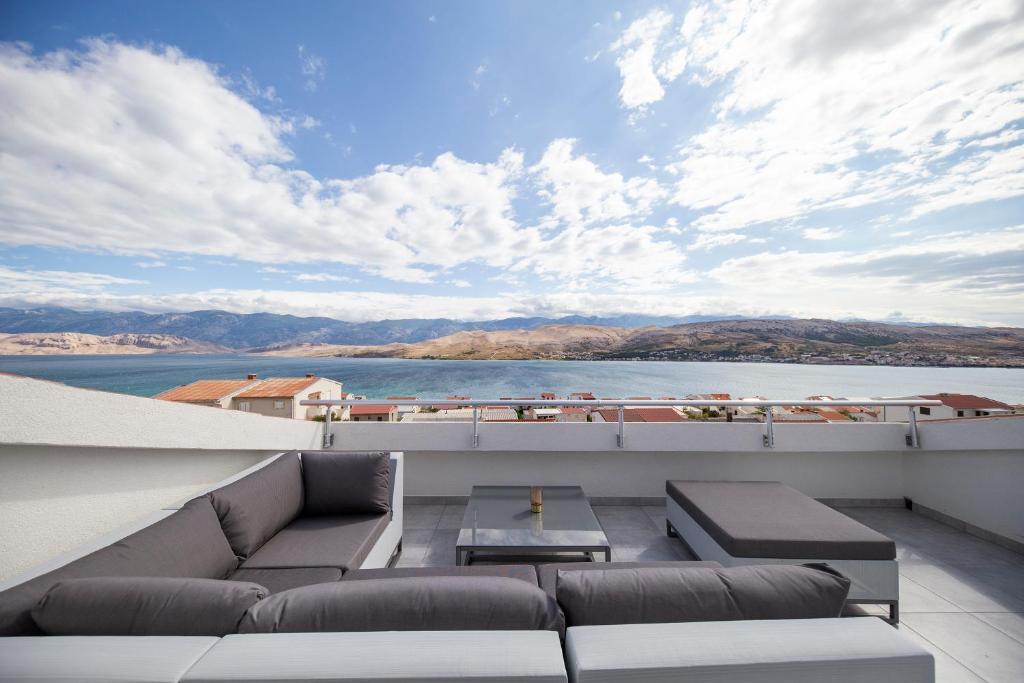 a balcony with couches and a view of the water at Apartments Haluga in Pag