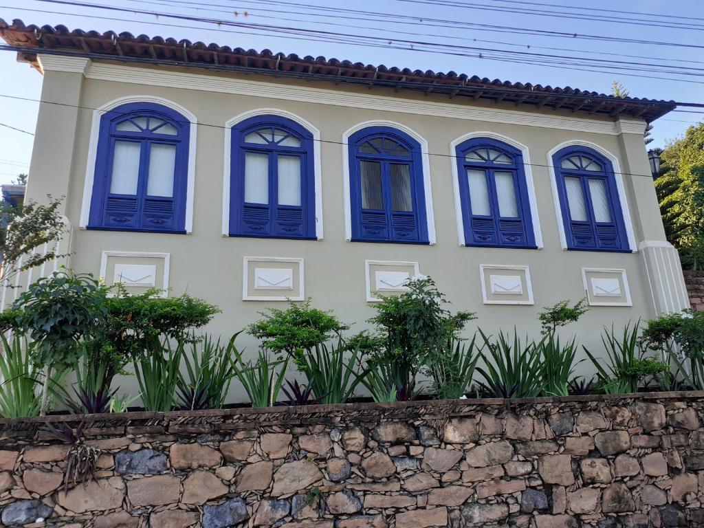 Casa con ventanas azules y pared de piedra en Pousada Raio de Sol, en Lençóis