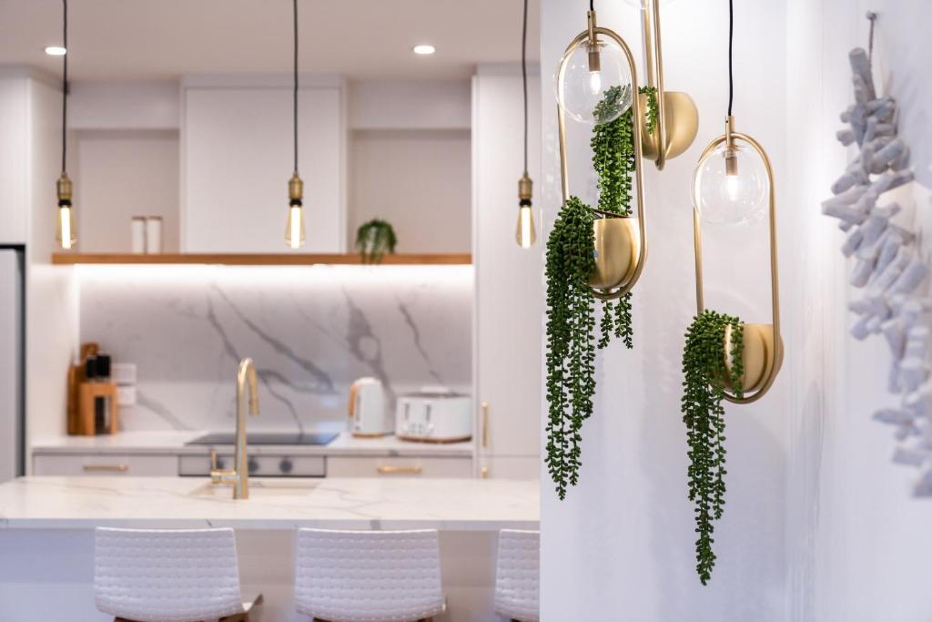 a kitchen with white cabinets and white chairs and plants at Stay Mission Bay in Auckland