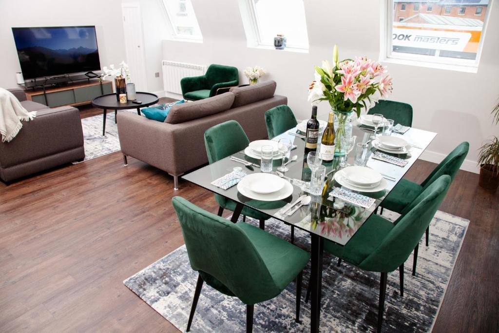 uma sala de estar com uma mesa e cadeiras verdes em High Life Serviced Apartments - Old Town em Swindon