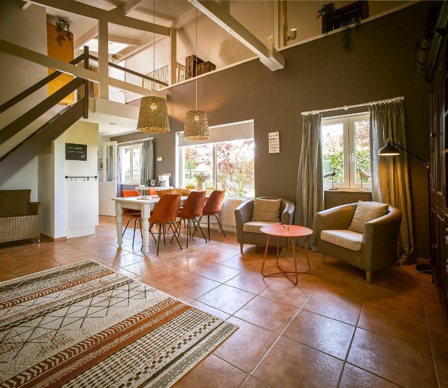 Vakantiewoning Cha Nostra في Moorveld: غرفة معيشة مع كراسي وغرفة طعام