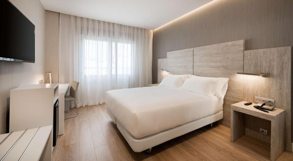 a hotel room with a white bed and white walls at NH Madrid Chamberí in Madrid