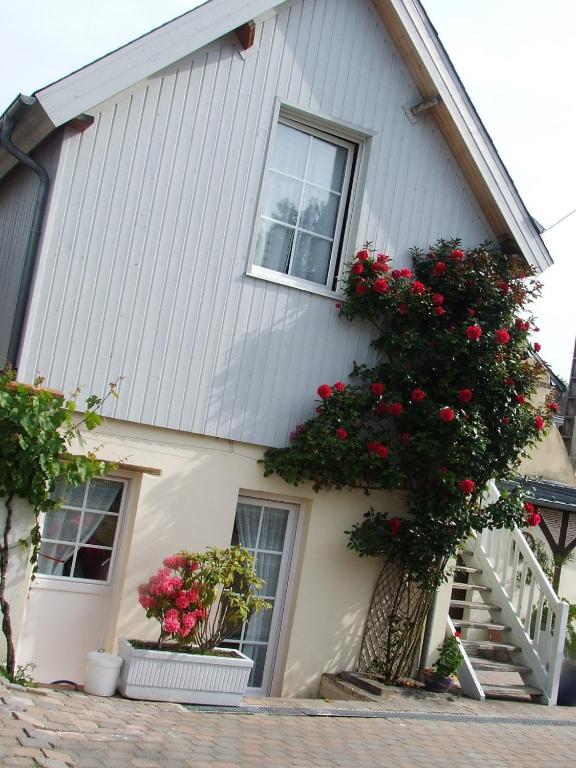une maison avec des fleurs rouges sur son côté dans l'établissement Gite les Orchidées, à Honfleur