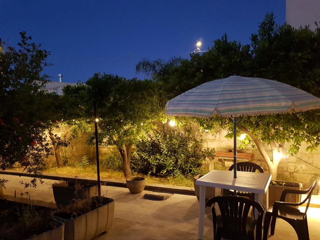 - une table avec un parasol sur la terrasse la nuit dans l'établissement Casa Vacanze Nonna Maria, à Carpignano Salentino