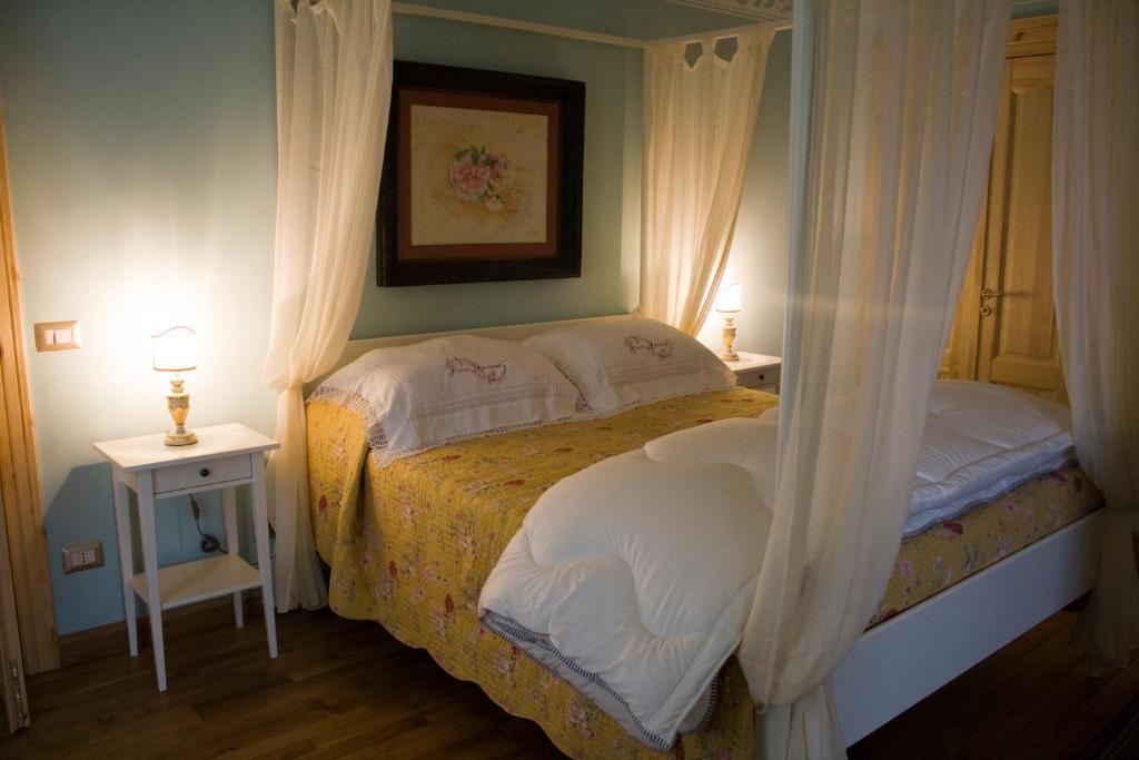 1 Schlafzimmer mit einem Bett mit Vorhängen und 2 Tischen in der Unterkunft Casarosa B&B de Charme in Cassano delle Murge