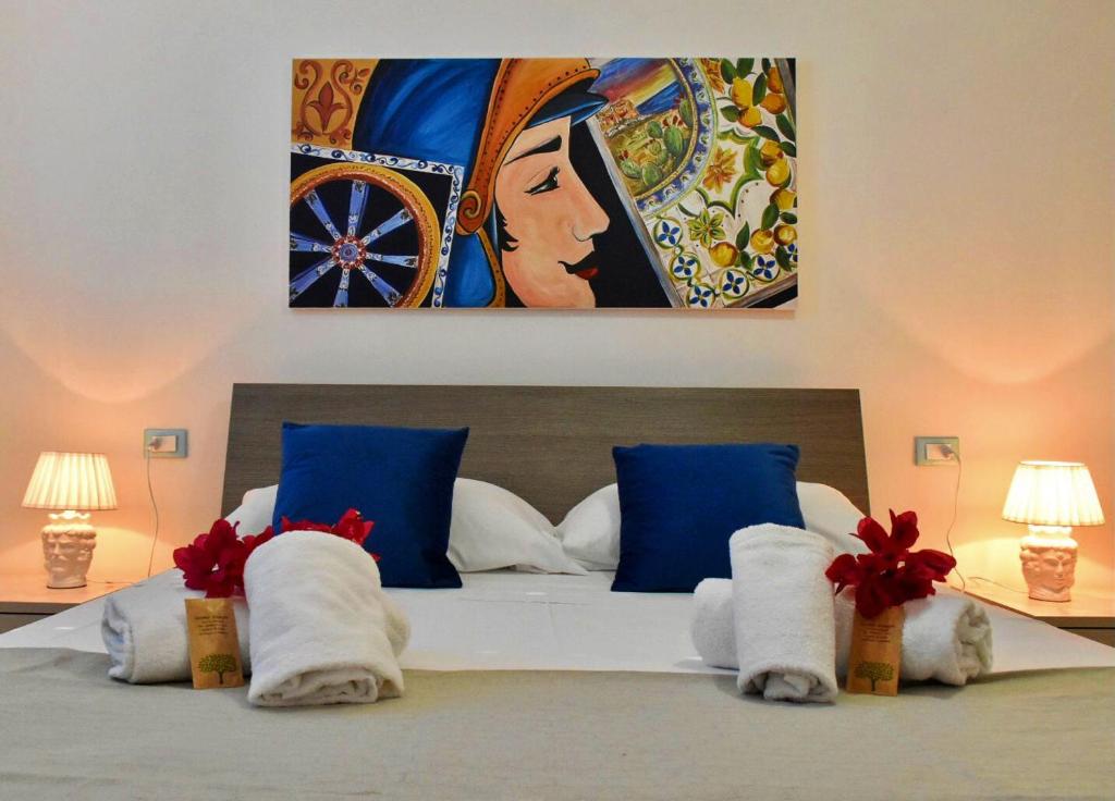 a bedroom with a bed with blue pillows and a painting at Casa Nettuno Favignana in Favignana