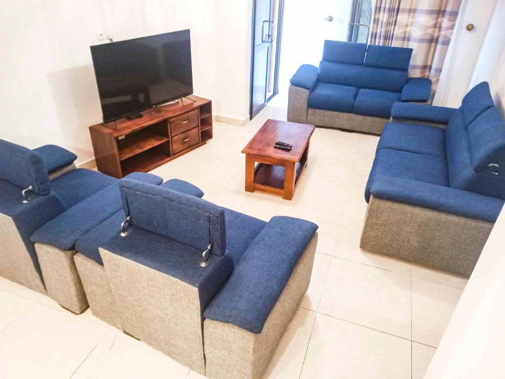a living room with blue couches and a flat screen tv at Appartement F4 Climatisé niveau Etage à Totsi près de la maison ADEBAYOR in Agbalé Pédo