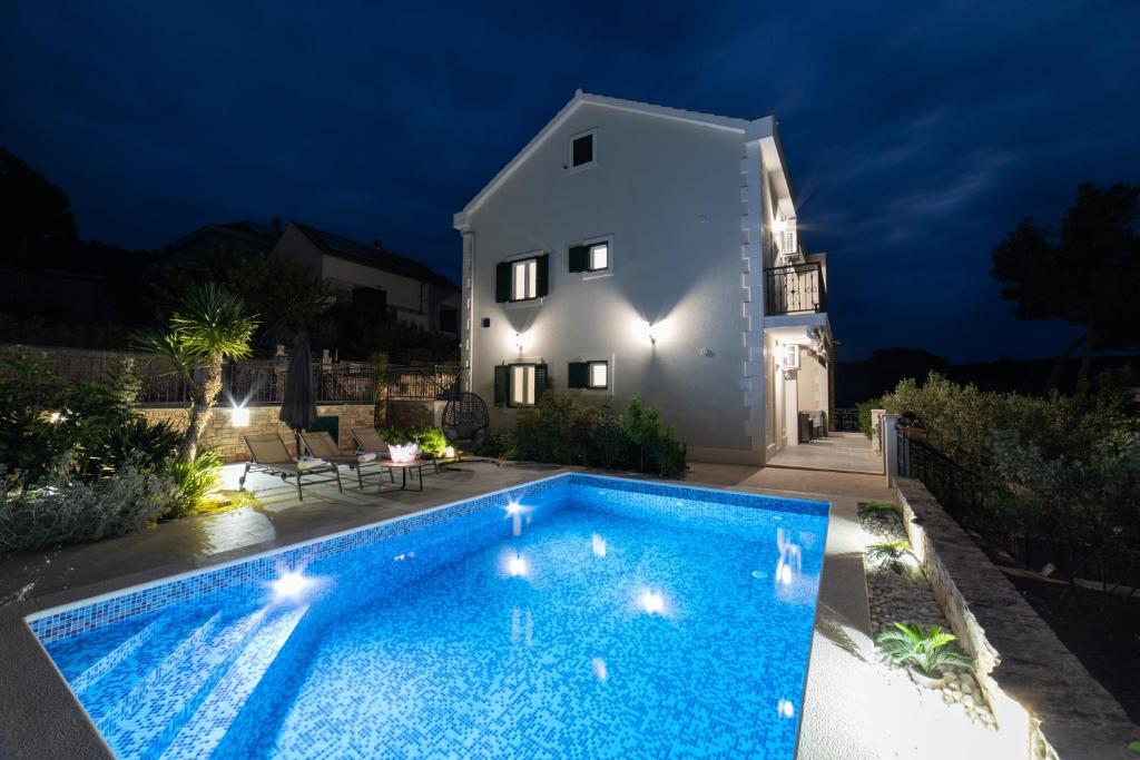 a swimming pool in front of a house at night at Villa Sun Garden - 4 star villa with heated swimming pool, quiet bay, BBQ, 50m from the sea in Milna