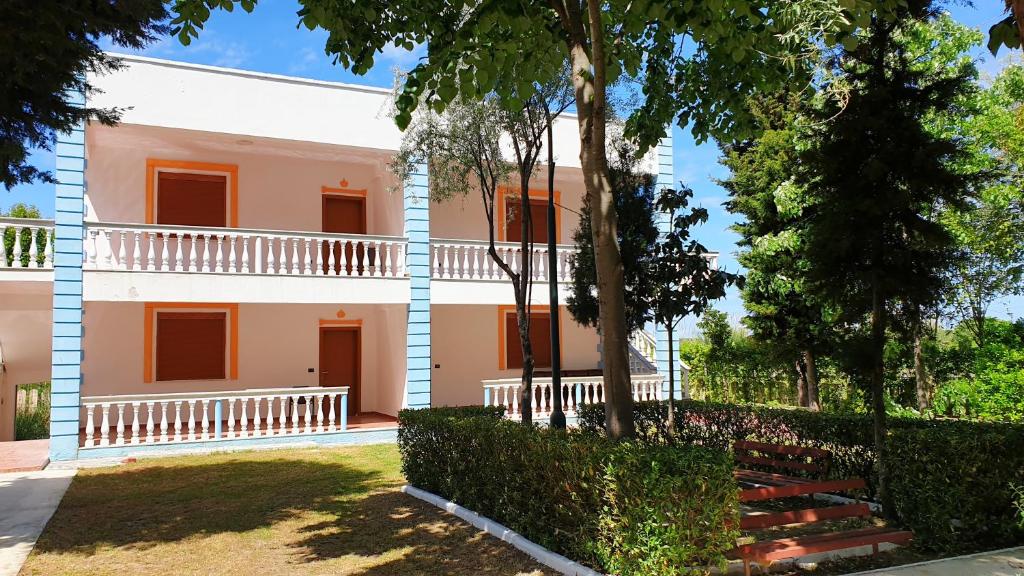 ein großes weißes Gebäude mit Bäumen davor in der Unterkunft Vila Gridi- Apartamente me Qera in Spille
