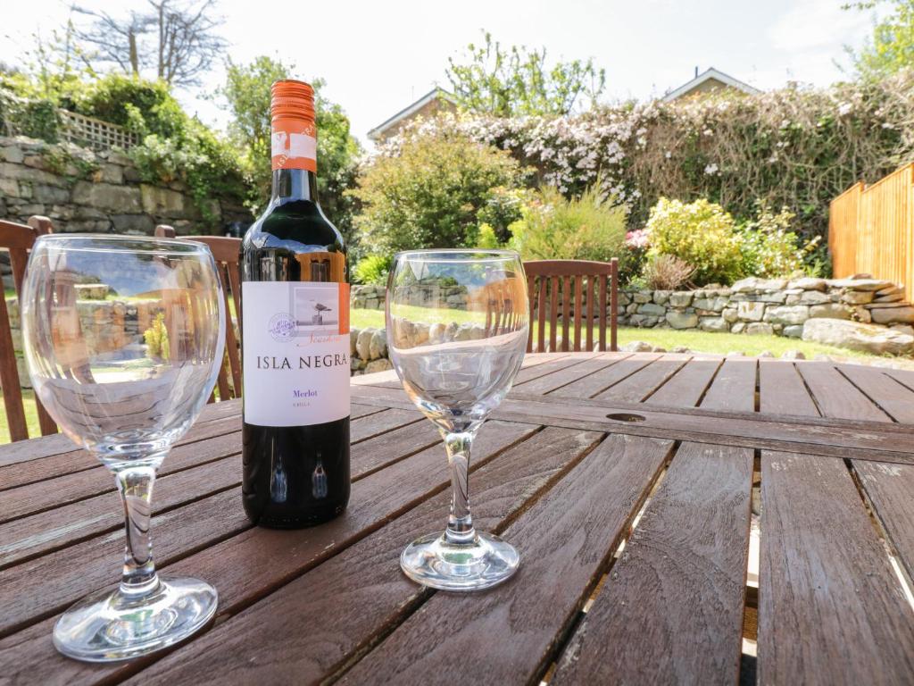 a bottle of wine and two wine glasses on a wooden table at Clyd Fan in Harlech