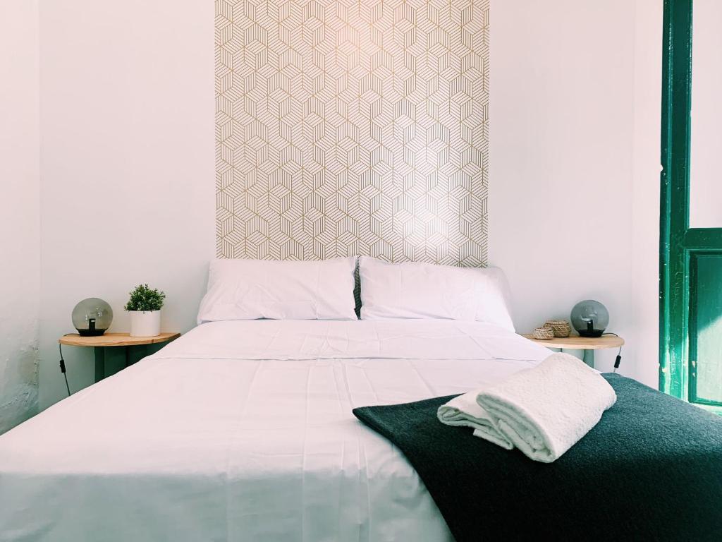 Una cama blanca con dos toallas encima. en Maria Magdalena - Room 8, en Málaga