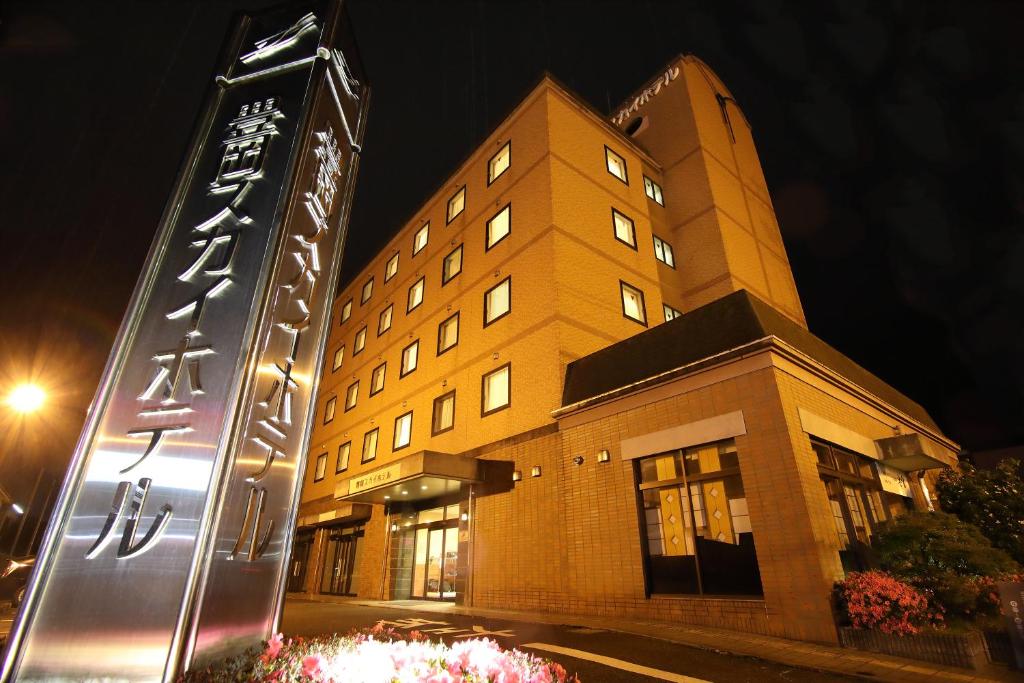 un edificio con un cartel delante de él por la noche en Toyooka Sky Hotel, en Toyooka