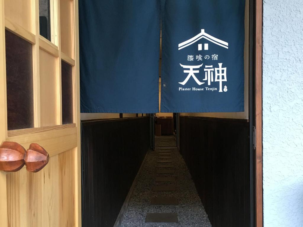 a long hallway with a blue banner and shoes at Shikkuinoyado Tenjin in Matsue