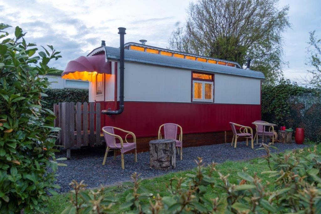 Une remorque rouge et blanche avec des chaises et des tables dans l'établissement De Wagen, à Egmond-Binnen