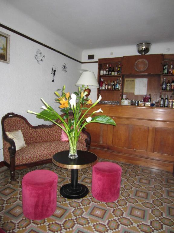 una stanza con un tavolo con un vaso di fiori e due sgabelli di Hotel Belle Vue a Le Lavandou