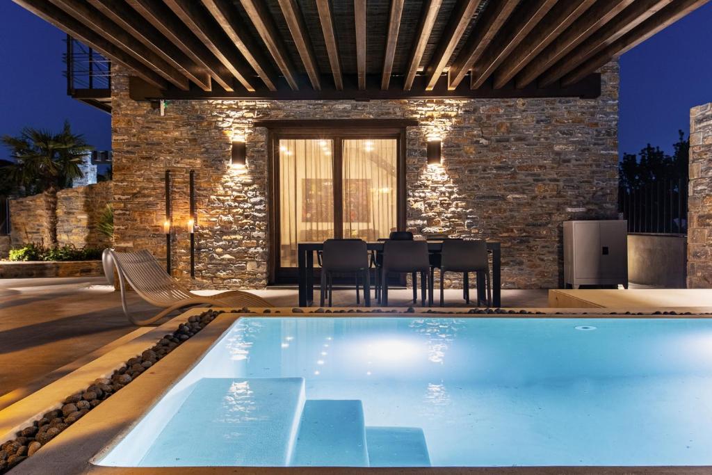 an indoor swimming pool with chairs and a house at Lethe Villas with Private Pool Kato Gatzea Greece in Kato Gatzea