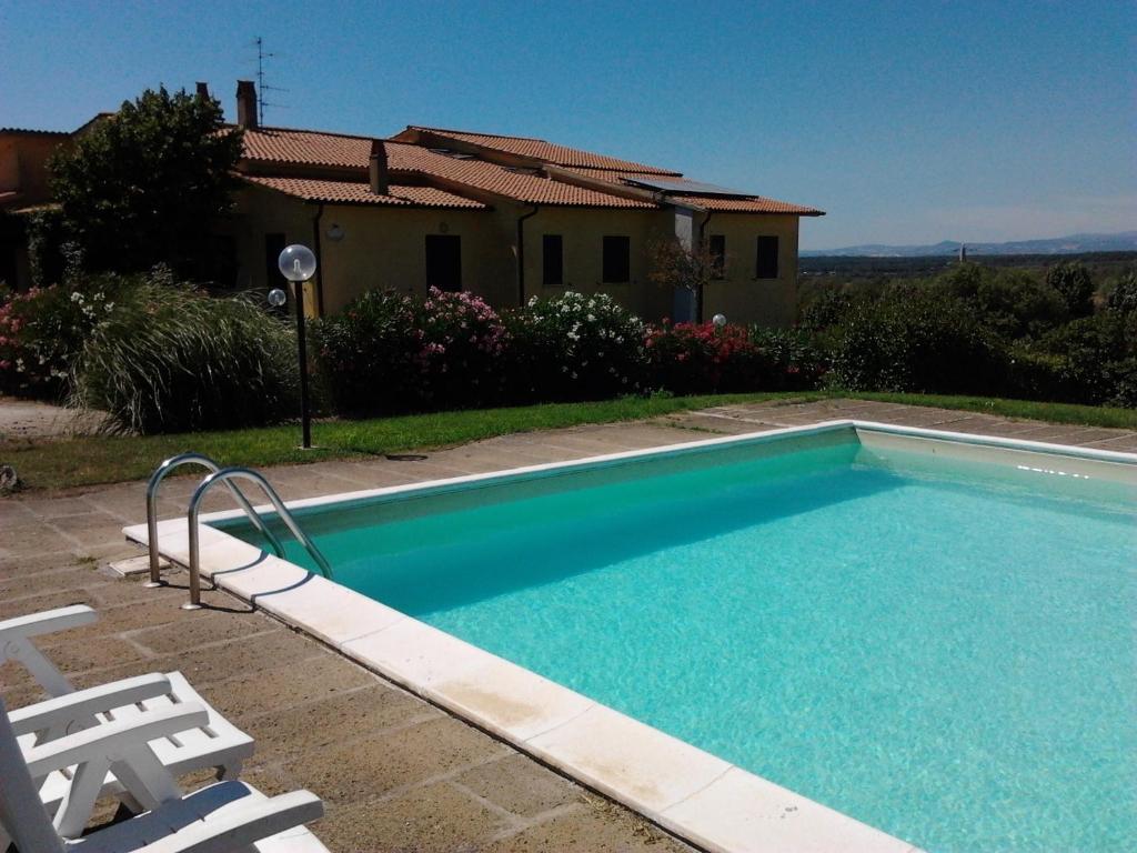 einen Pool mit zwei Stühlen und ein Haus in der Unterkunft Agriturismo Poggio Torreano in Farnese