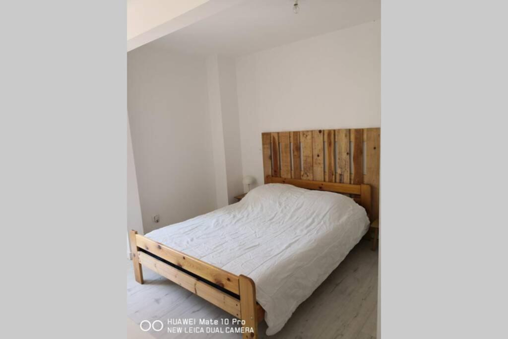 Appartement avec Jardin privatif centre ville في هييريس: سرير مع اطار خشبي في الغرفة