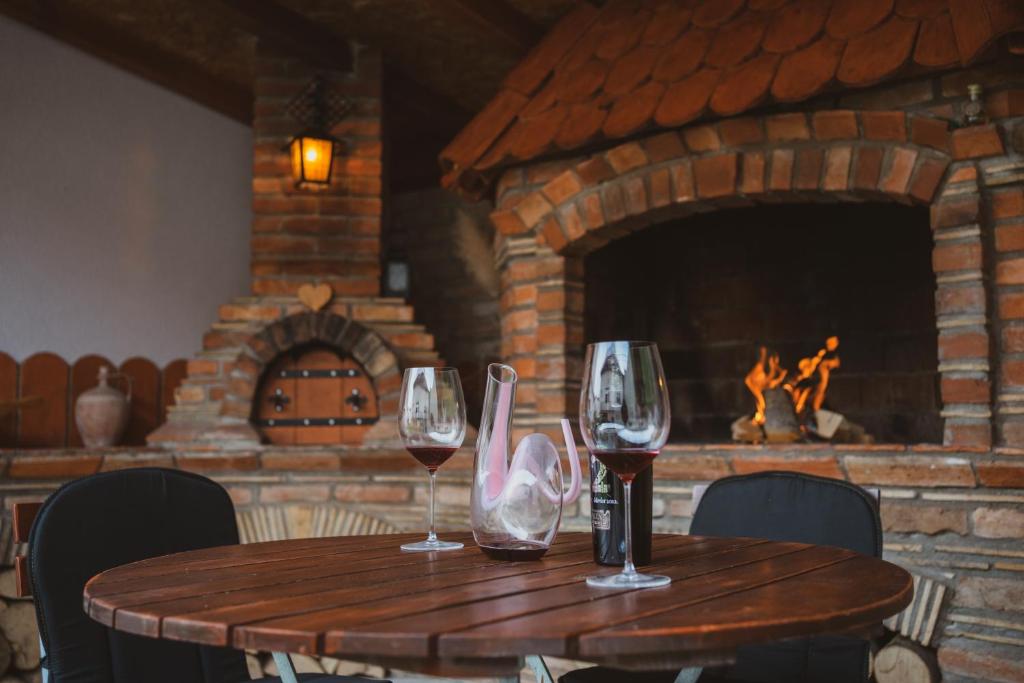 a wooden table with wine glasses on it with a fireplace at Kuca Magnolija in Nuštar