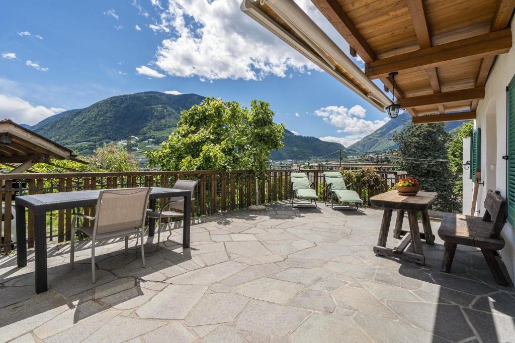 d'une terrasse avec une table, des chaises et des montagnes. dans l'établissement Ferienwohnung Golserhof, à Merano